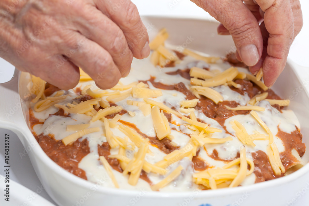 Adicionando quesos a la lasagna parmesana