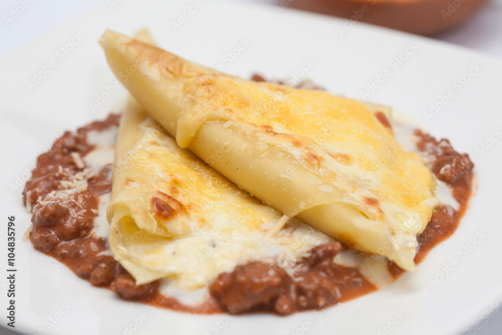 Triángulos de lasagna parmesana servidos sobre salsa bolognesa