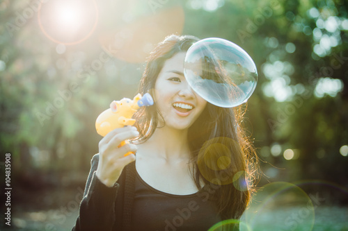 Beautiful young woman playing bubble in sunlight. Vintage film c