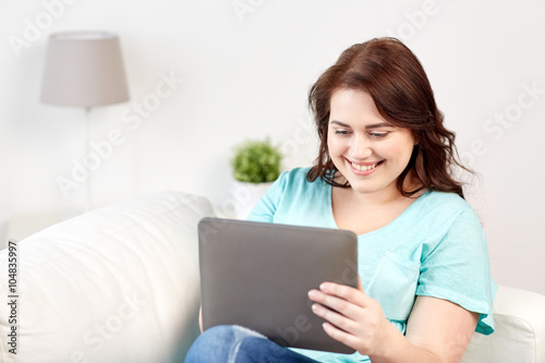 happy young plus size woman with tablet pc at home