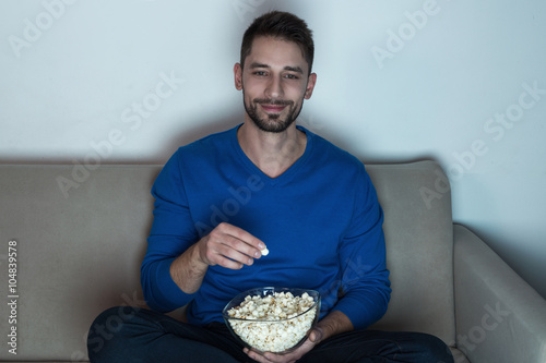 Man eating popcorn, watching television 