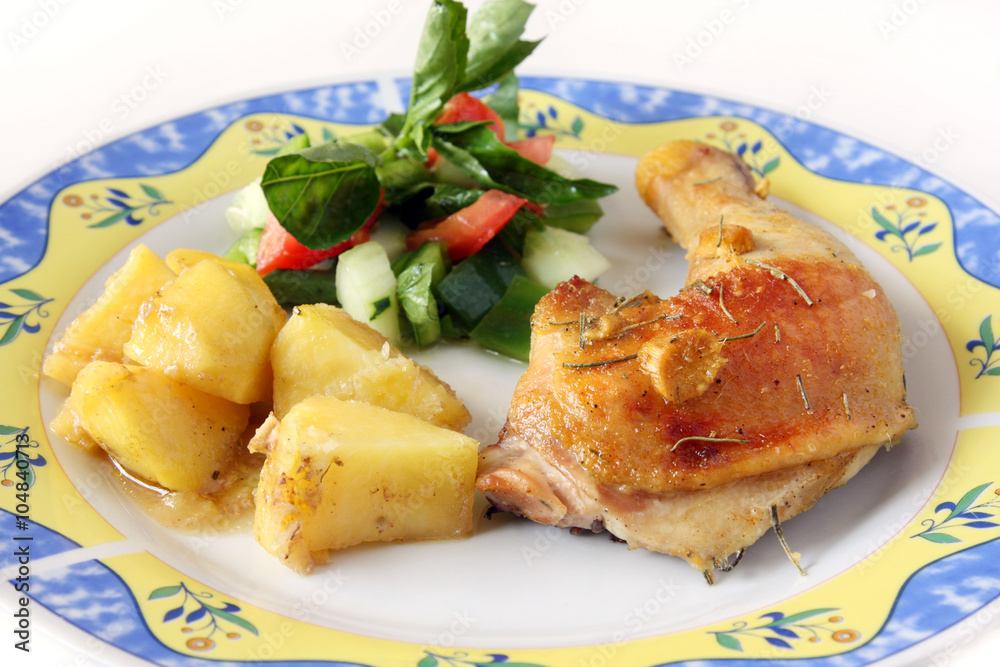 isolated, served homemade baked chicken leg with potatoes and vegetable salad on plate
