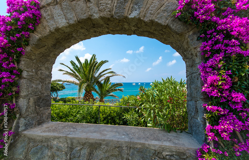 Sea view through the arch framed by bougainvillea