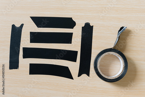 Set of different black adhesive duct tape pieces on wooden background photo