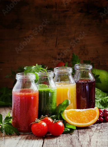 Bottles with fresh juices from fruits and vegetables on an old w