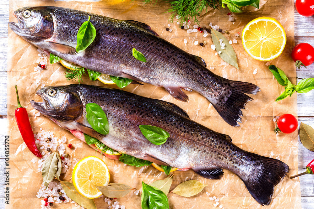 raw trout fishes on the baking papper with lemon slices raw trout fishes on the baking papper with lemon slices