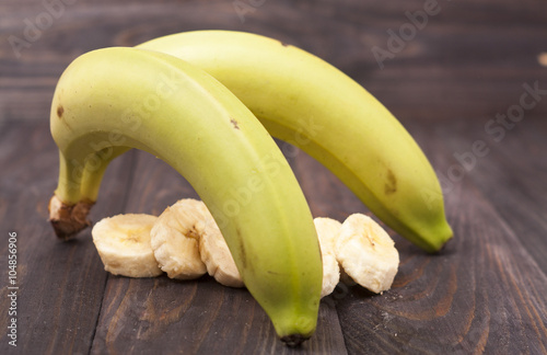 green banana with slices on wooden background