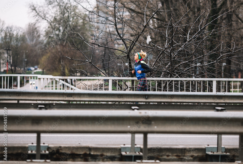 Fototapeta premium Female in sports wear jogging in city environment.