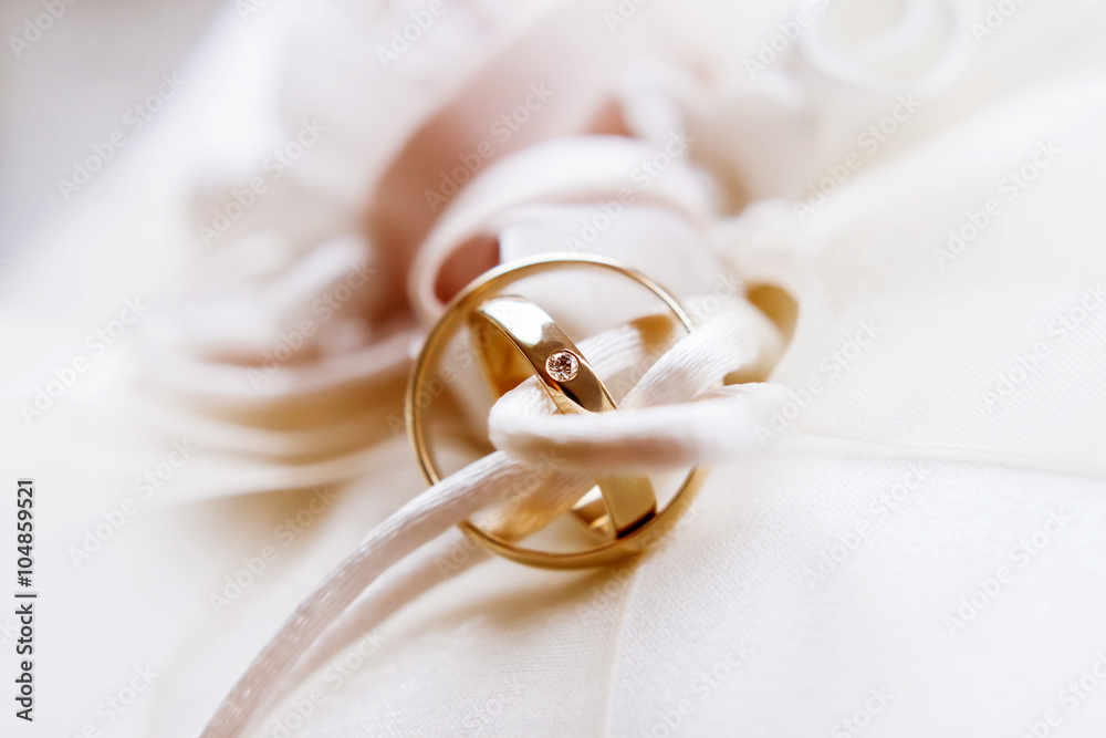 Golden wedding rings with diamond on silk fabric. Wedding jewelry details. Golden wedding rings with diamond on silk fabric. Wedding jewelry details.