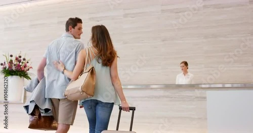 Attractive happy couple arriving at hotel reception travelling on vacation