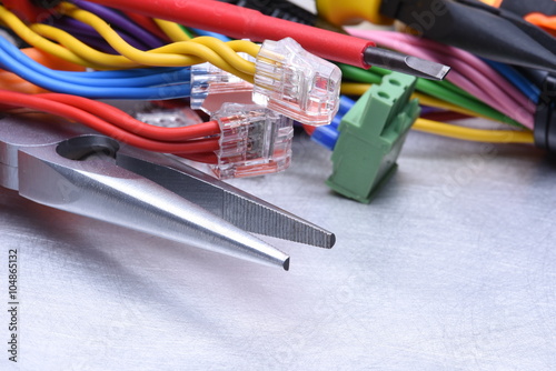 Tools for electrician and cables on grey metal surface