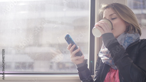 Young woman reading through her phone whilst on a train journey, in slow motion
