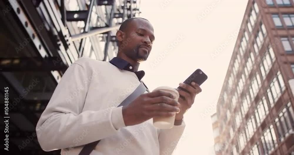African American businessman walking through city using smart phone