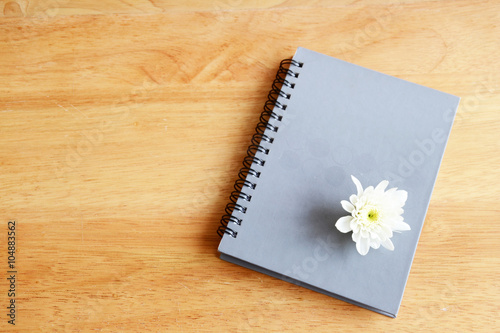daisy flower and notebook on wood table
