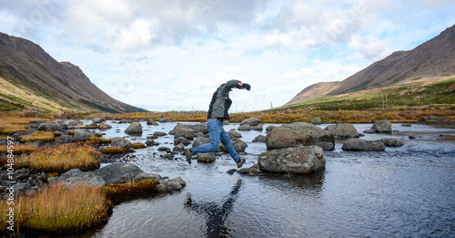 Man crosses a stream jumping rock to rock