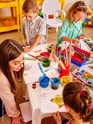 Children with teacher woman learn painting on color paper in  art class kindergarten . Top view.