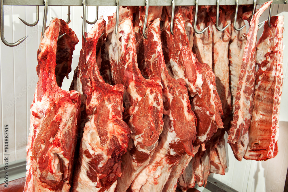 Large raw meat loins on hooks
