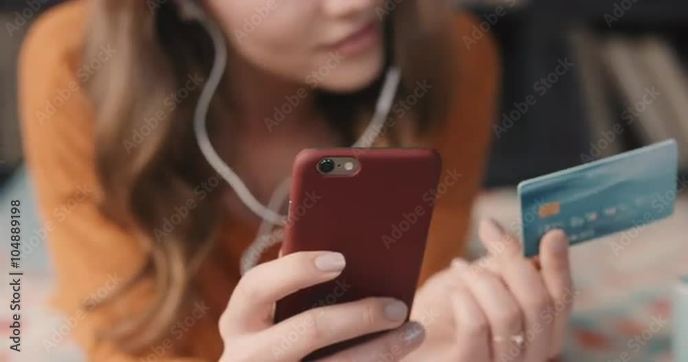 Beautiful woman shopping online with credit card and smart phone at home in trendy loft apartment