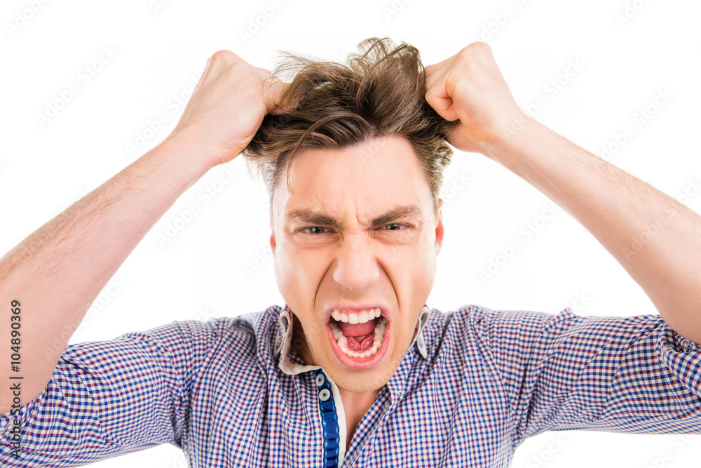 Close up portrait of young man screaming and holding his hair Close up portrait of young man screaming and holding his hair