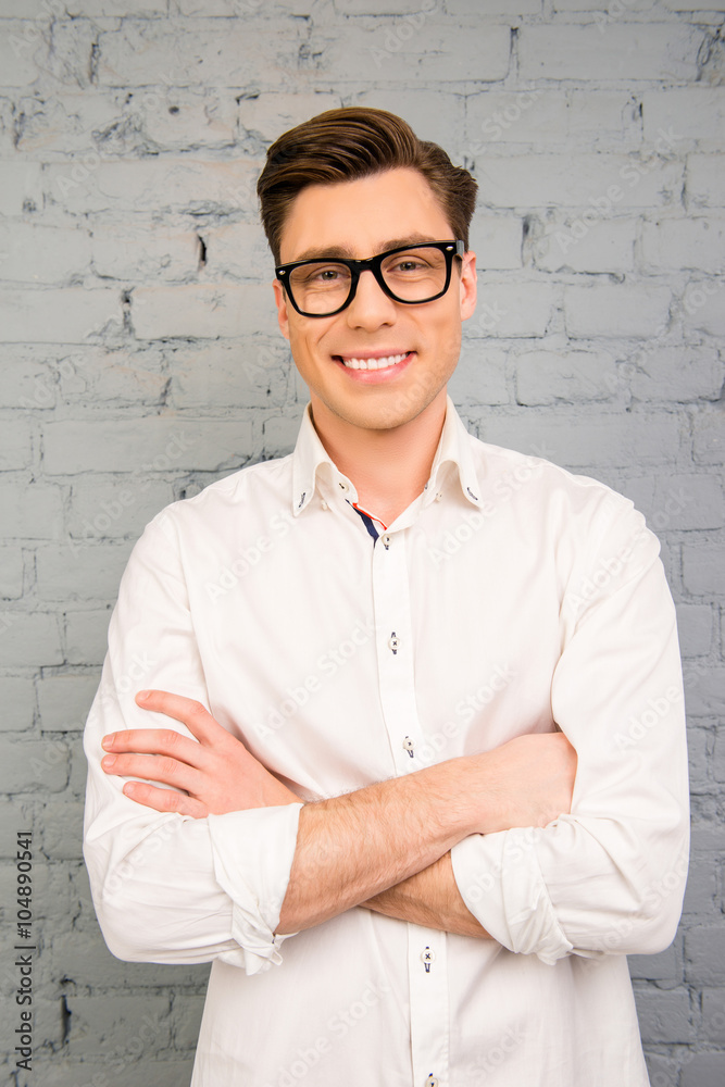 Attractive young man in glasses posing with crossed hands Attractive young man in glasses posing with crossed hands