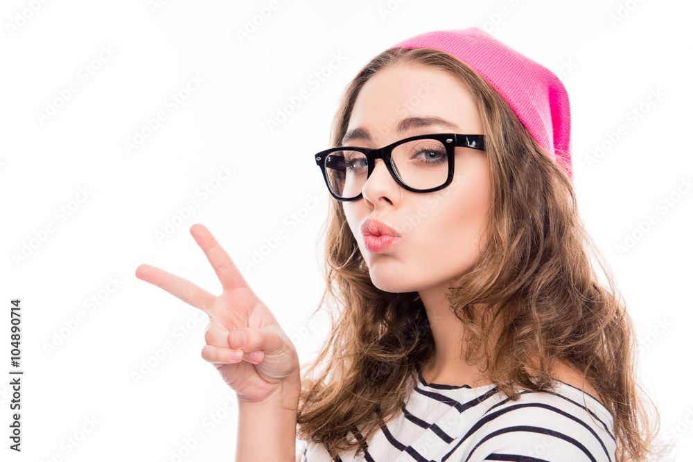smiling girl in hat and glasses showing two fingers and pouting smiling girl in hat and glasses showing two fingers and pouting