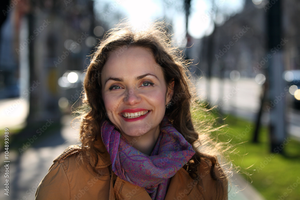 Beautiful woman with curly hair and beige jacket on the street Beautiful woman with curly hair and beige jacket on the street