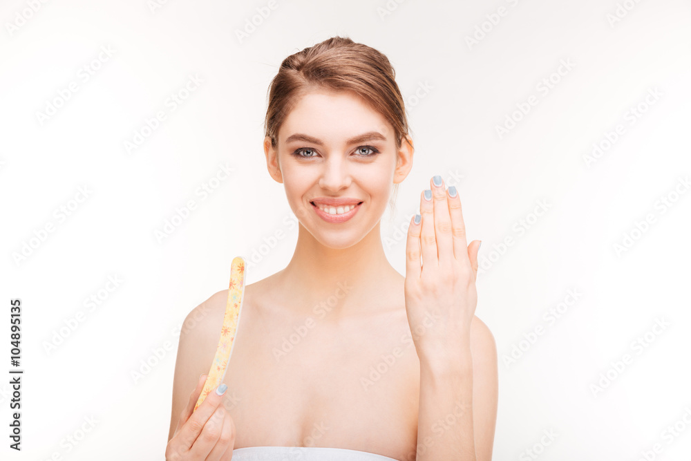 Happy young woman with nail file showing her nails Happy young woman with nail file showing her nails