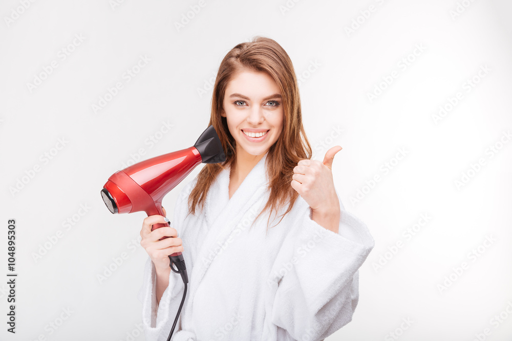 Cheerful woman holding hair dryer and showing thumbs up Cheerful woman holding hair dryer and showing thumbs up