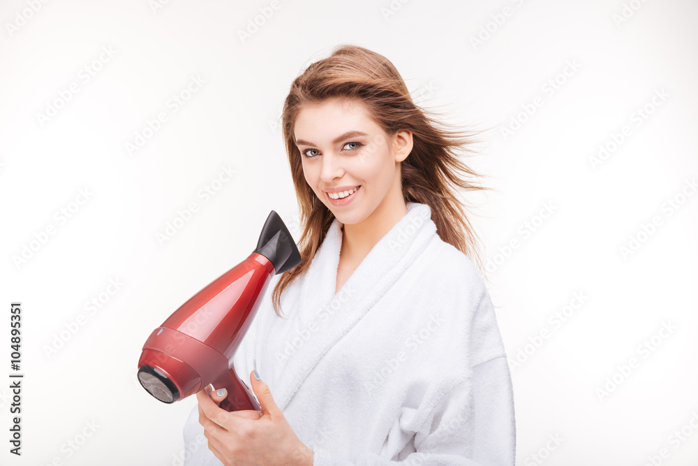 Happy attractive woman in bathrobe standing and using hair dryer Happy attractive woman in bathrobe standing and using hair dryer