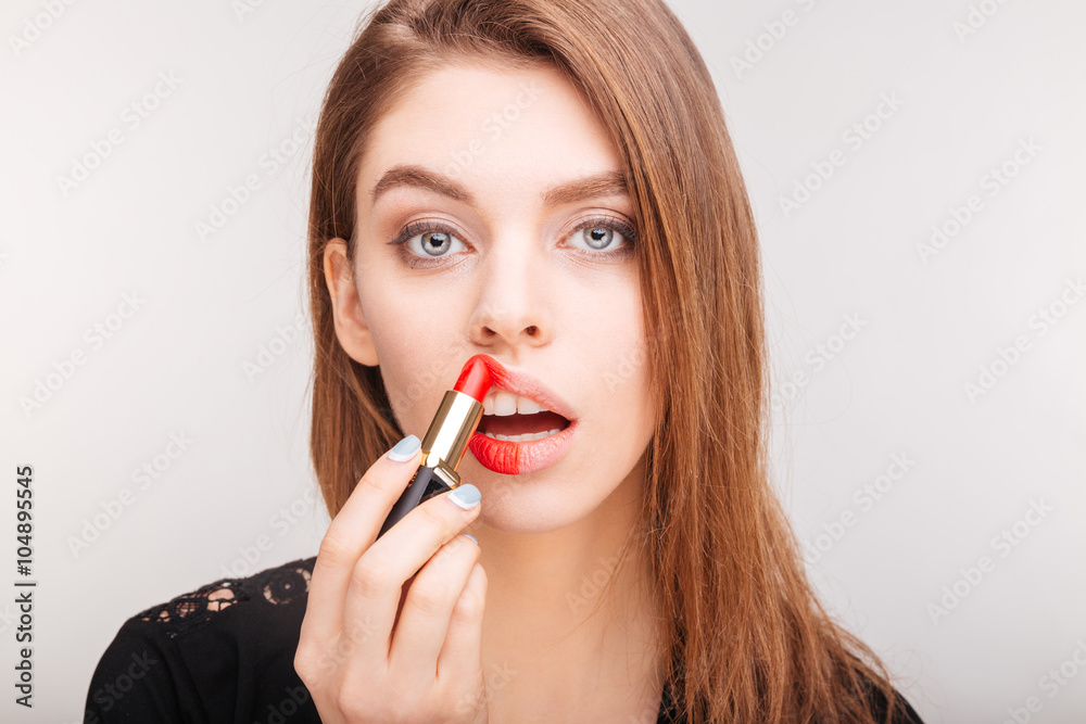 Beauty portrait of pretty woman doing makeup with red lipstick Beauty portrait of pretty woman doing makeup with red lipstick