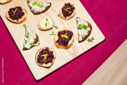Wooden tray of appetizers on pallet coffee table at banquet with beetroot, citron, green herbs and hummus.