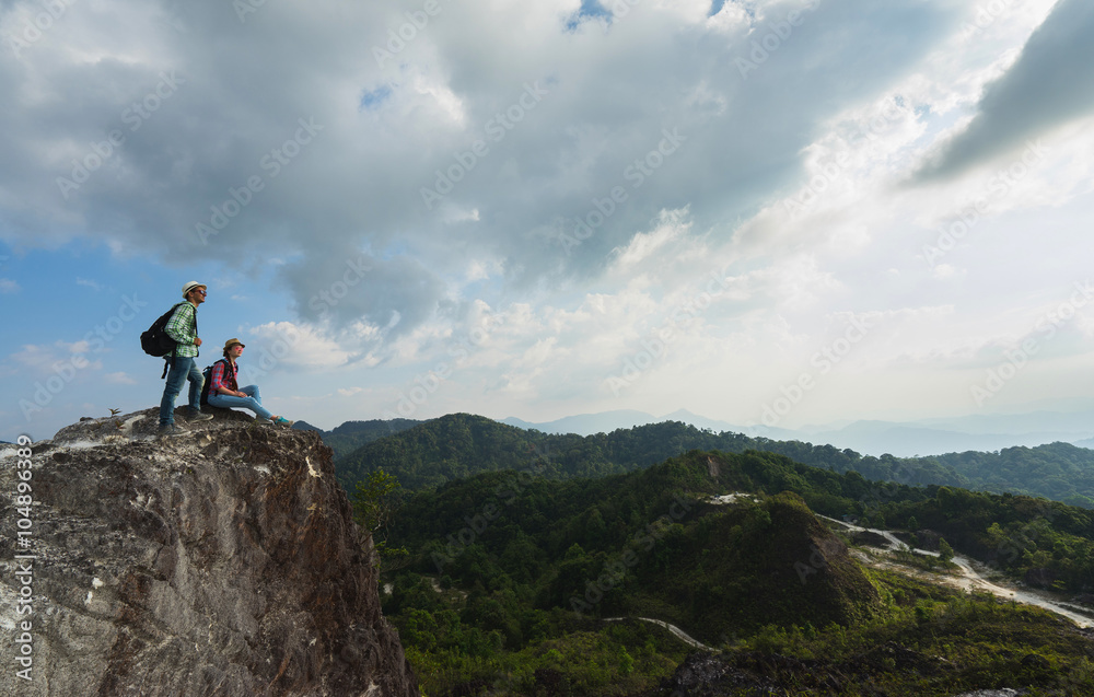 Young backpackers enjoying a valley view from top of a mountain. Travel concept