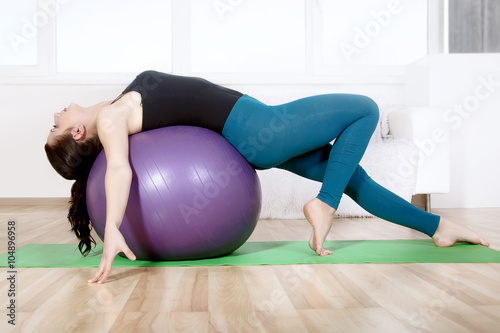 Girl doing stretching her body while lying on gym ball