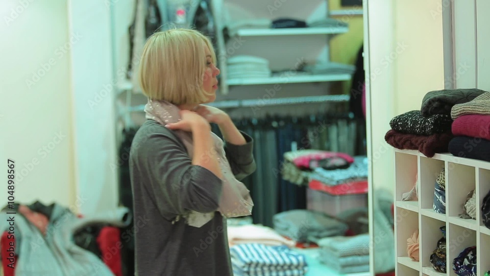 Woman trying on a scarf in a clothing store Woman trying on a scarf in a clothing store