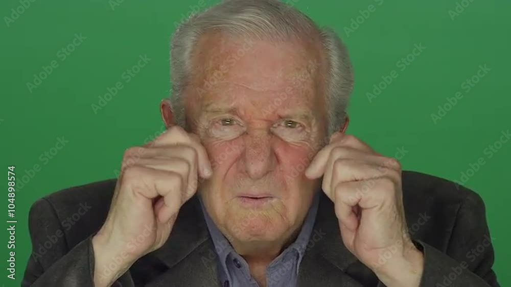 Older man confusingly staring, on a green screen studio background 