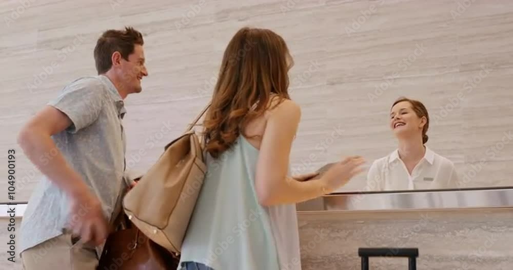 Attractive happy couple arriving at hotel reception travelling on vacation