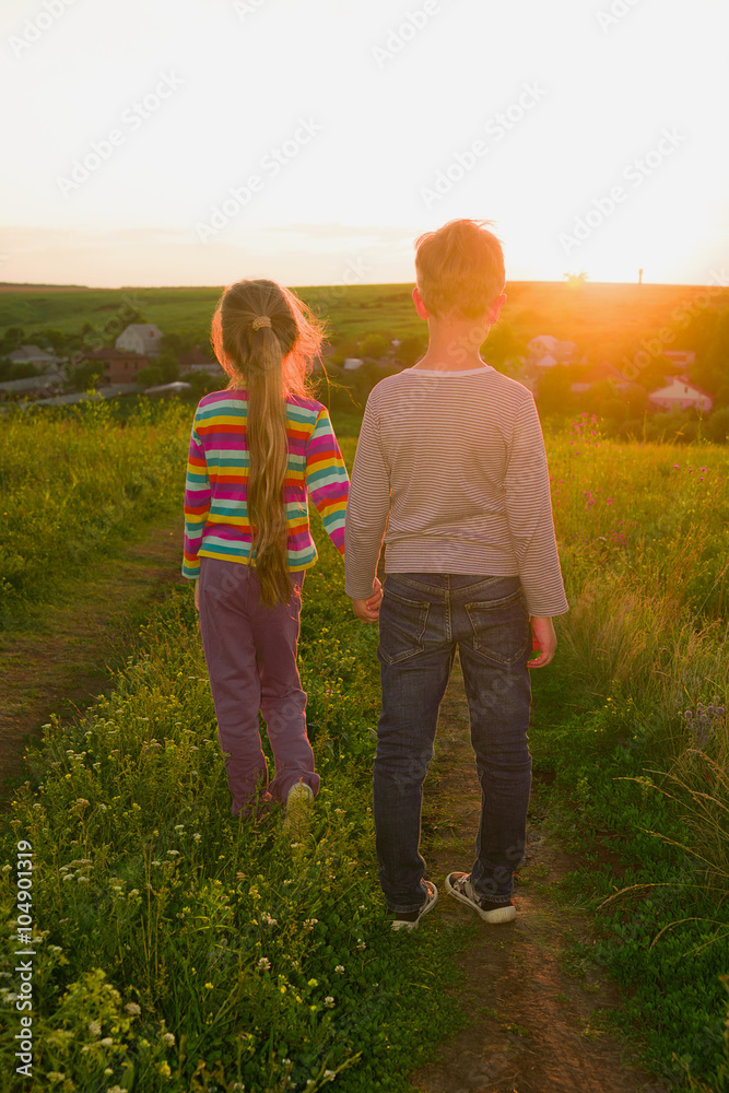 Boy and girl holding hands and walking along the road Boy and girl holding hands and walking along the road