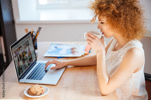 Woman photographer drinking coffee and working with laptop on workplace