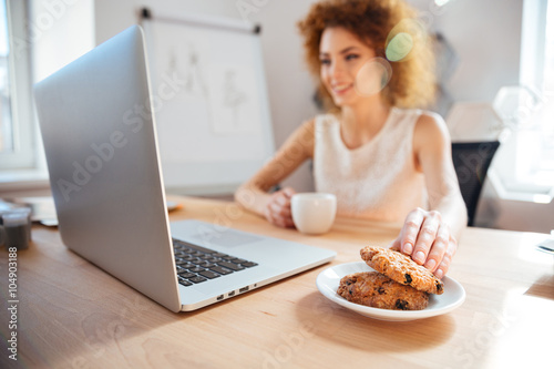 Smiling business woman drinking coffee with cookies on workplace © Drobot Dean