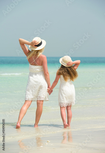 Back view of mother and daughter at tropical beach