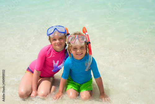 Smiling boy with sister wearing snorkeling gear on the beach