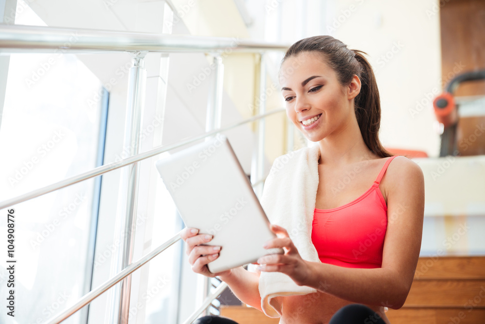 Happy cute young sportswoman using tablet in gym Happy cute young sportswoman using tablet in gym