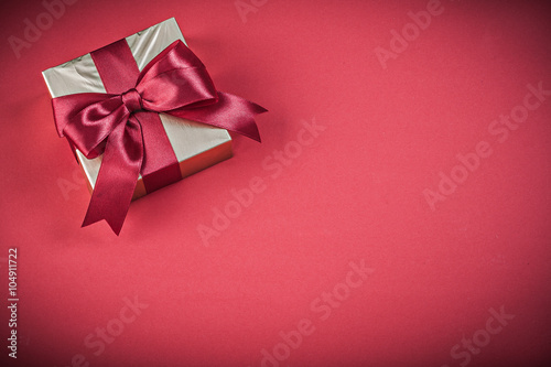 Packed present box with bow on red background holidays concept