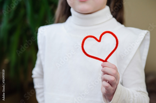 Fototapeta Naklejka Na Ścianę i Meble -  Red wire in the form of heart in the hands of a girl