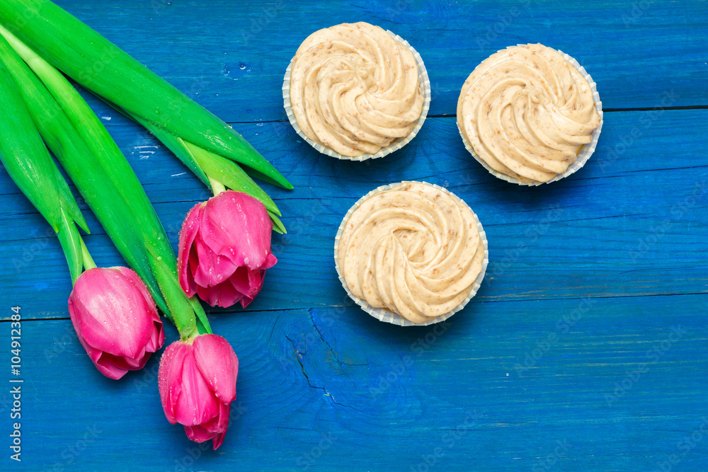 cupcakes with cream and tulips on blue boards cupcakes with cream and tulips on blue boards