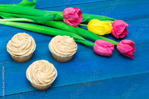 cupcake with cream and tulips on blue boards