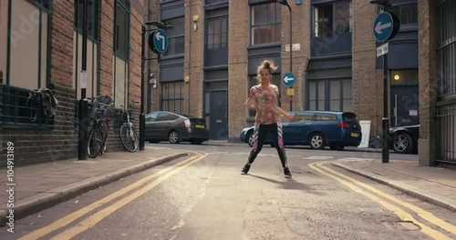 Contemporary funky mixed race woman street dancer dancing freestyle in the city