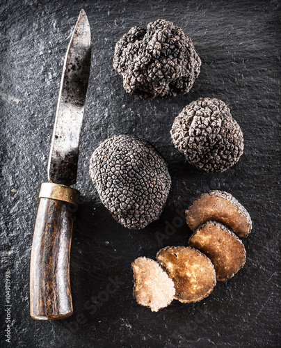 Black truffles and truffle slices on the graphite board.