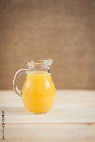 Orange juice in clear jar on a wooden background