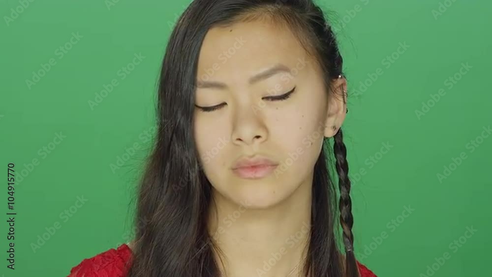 Young Asian woman staring and looking serious, on a green screen studio background Young Asian woman staring and looking serious, on a green screen studio background